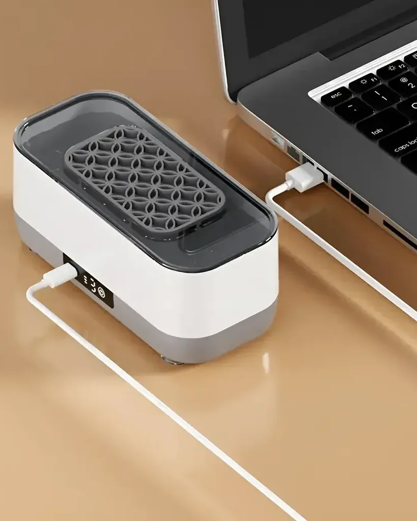 Limpiadora ultrasónica cargando por USB junto a una notebook